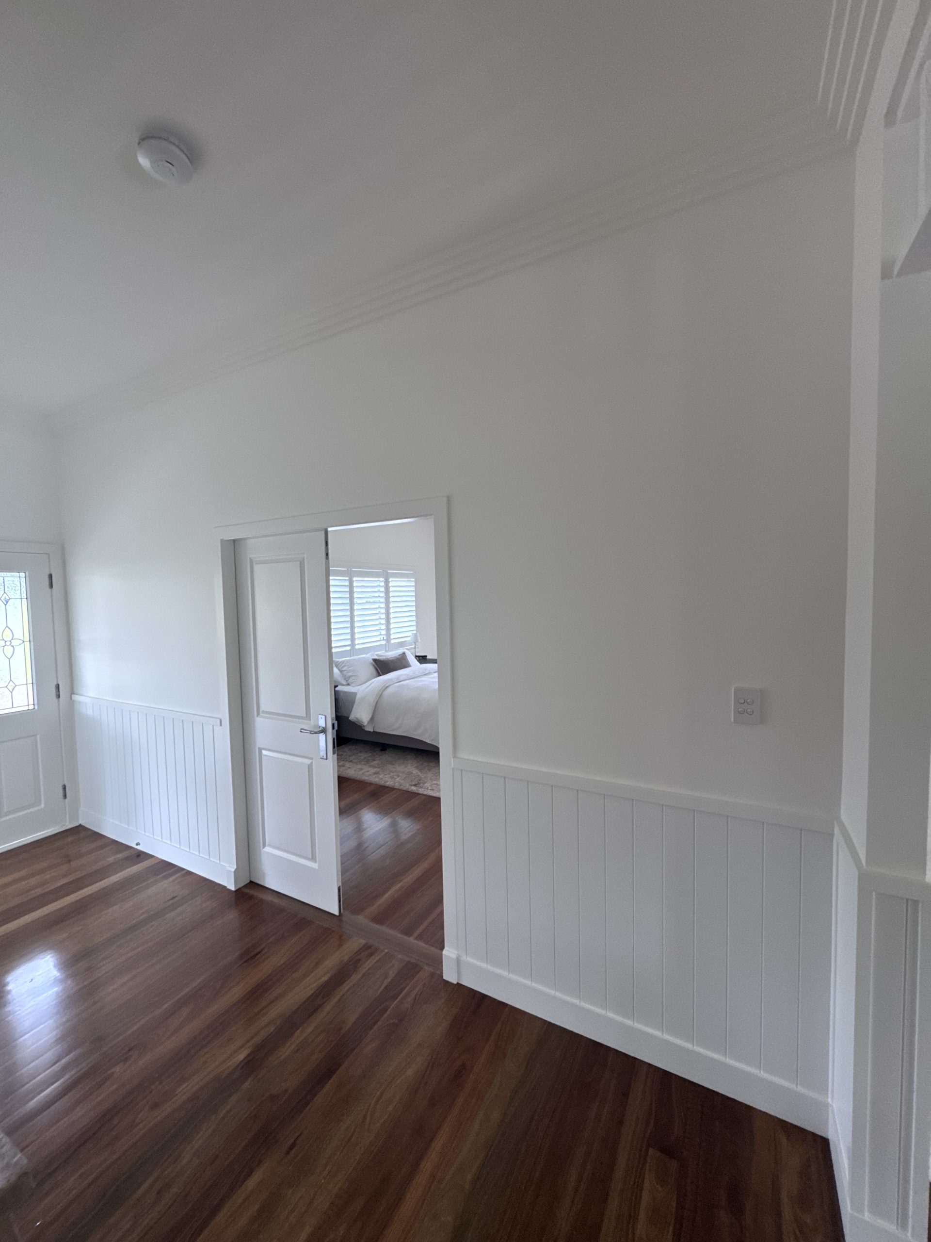 White hallway walls with lower wall panelling and an open doorway